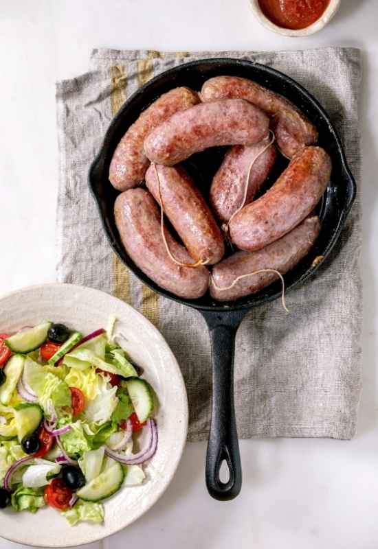 salsiccia in a pan with salad on a plate