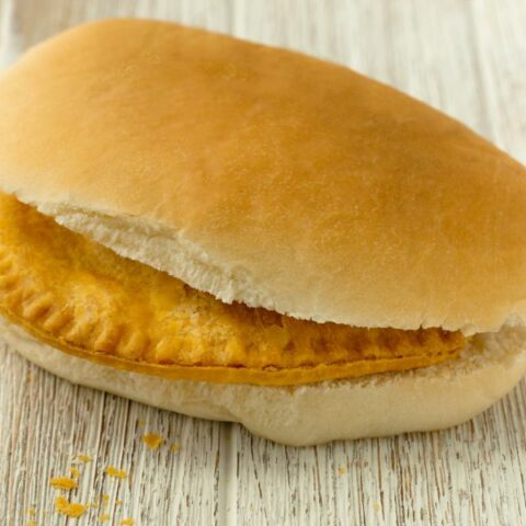 Bread roll on a board with a pattie inside.
