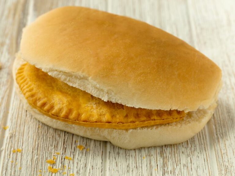 Bread roll on a board with a pattie inside.
