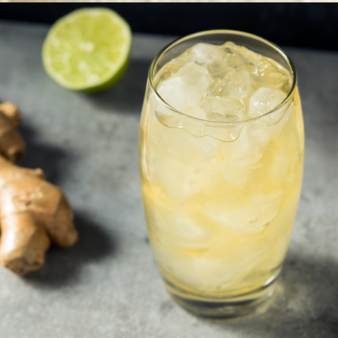 cocktail in a glass with ice with ginger and lime on the side
