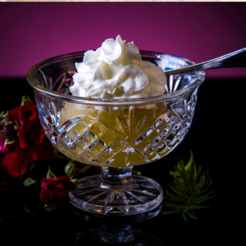Poached apple with cream in a glass bowl with a stem