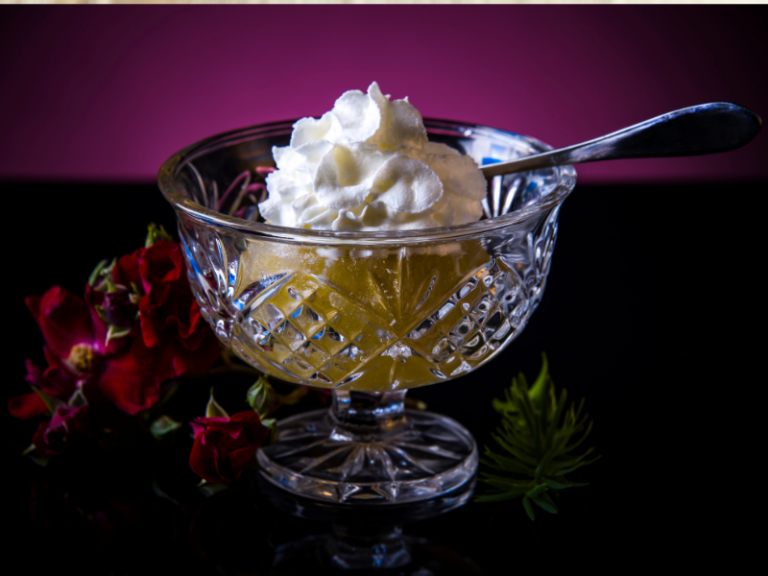 Poached apple with cream in a glass bowl with a stem