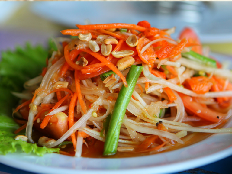 White plate with papaya salad on top