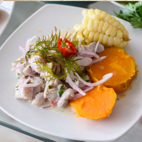 White plate with chicken, sweet potatoes, onions, corn and herbs