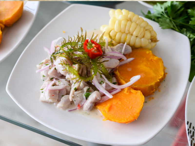 White plate with chicken, sweet potatoes, onions, corn and herbs